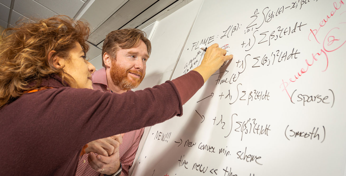 Francesca Chiaromonte (left) and Matthew Reimherr discuss functional data analysis techniques critical to the interpretation of INSIGHT data. Credit: Nate Follmer